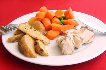 served healthy meal: baked potatoes, carrots, green peas and chicken
