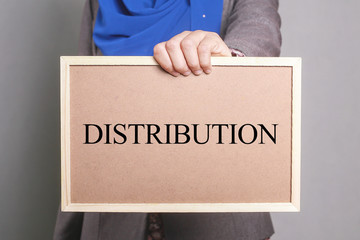 Businesswoman holding a softboard written DISTRIBUTION