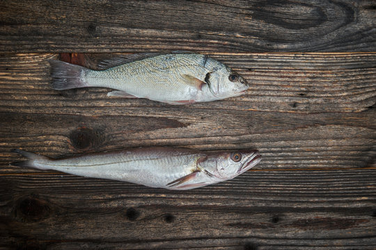 Raw fish over wooden background, top view