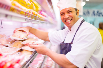 butcher organizing meat products in supermarket