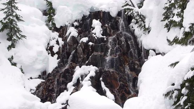 Snow Covered Rocks Frame Winter Waterfall of Snow Melt Runoff