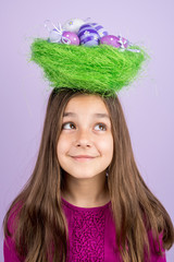 Little girl and nest with Easter eggs over her head