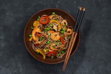 Buckwheat noodles with seafood in a bowl, top view