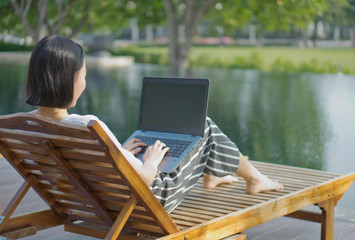 Woman using laptop computer by the pool