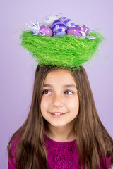 Little girl and nest with Easter eggs over her head
