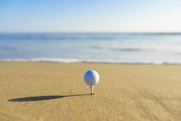 Golf Ball on a tee at a California beach with white wave in Pacific Ocean