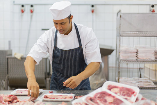 mid age butcher packing meat pieces