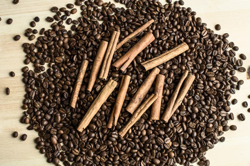 cinnamon sticks are on the pile of coffee beans on wood table