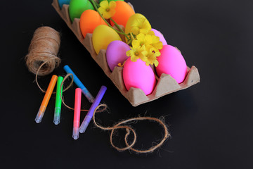 Colored Easter eggs with colorful markers, rope and spring yellow flowers