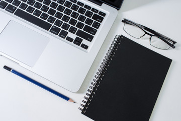 Work desk with laptop, glasses, notebook and pencil