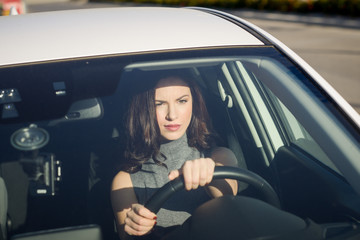 Brunette woman driving a white car in urban background
