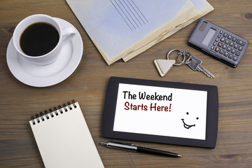 The Weekend Starts Here! Text on tablet device on a wooden table