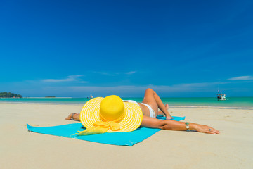 Fototapeta na wymiar Woman in yellow bikini lying on tropical beach