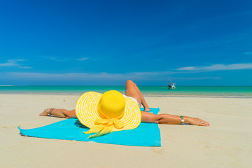 Woman in yellow bikini lying on tropical beach
