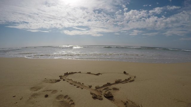 Heart shape symbol on sand next to the ocean