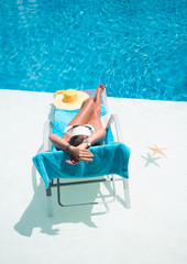 Woman in hat relaxation at swimming pool bed