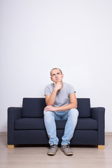 idea concept - dreaming man sittin on sofa over white wall