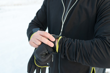 Runner using heart rate monitor, smartwatch checking performance or GPS. Man athlete looking at stopwatch. Technology for tracking activity. Outside, snow, winter