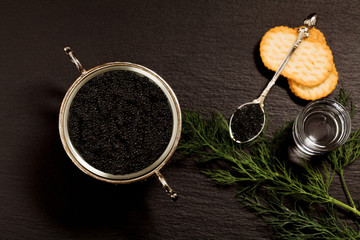 Black caviar served on crackers with vodka and additives