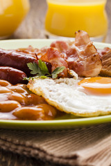 Full english breakfast with bacon, sausage, fried egg, baked bea