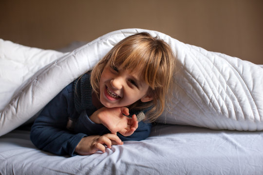 Bambina gioca a letto sotto il piumone