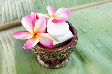 Mini set of shower bath soap with flowers frangipani on green ba