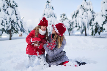 daughter with mother play in snow-covered park