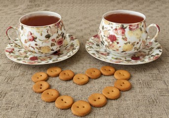Two cup of tea and some cookies on table