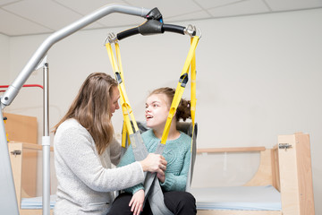 Disability a disabled child being cared for / Disability a disabled child being cared for by a special needs carer using specialist lifting equipment