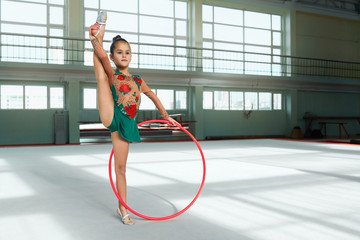 Beautiful girl gymnast performs with  hoop stretch