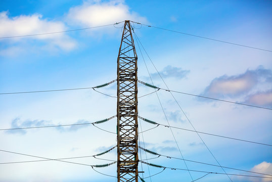 Electricity pylon silhouetted against blue sky background. High voltage tower. Electric wires.