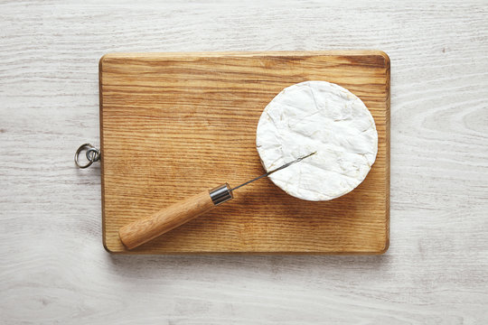 Isolated camembert with knife inside on table