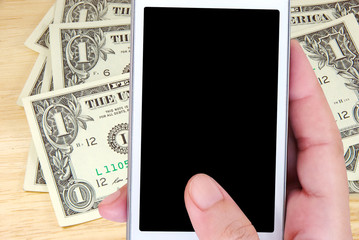 Hand holding smart phone over dollar bills background