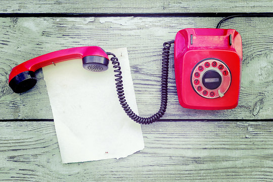Vintage red phone and a piece of paper to write