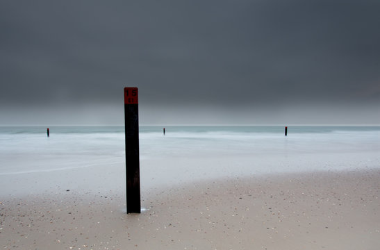 Strandpaal op sombere dag op zand