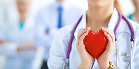 Deurstickers Huisarts Vrouwelijke arts met een stethoscoop die hart vasthoudt