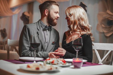 Beautiful young couple with glasses of red wine in luxury restaurant