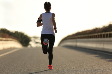 young fitness woman runner running on sunrise road