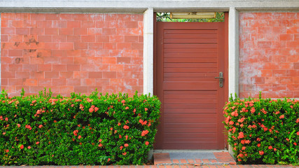 Door and Red Bricks Wall with Red Flowers