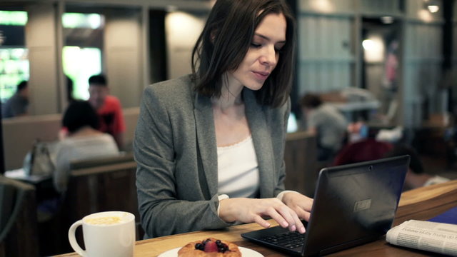 Young businesswoman working on laptop and drinking coffee in cafe HD
