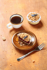 Cut of Rustic Mini Tart with Honeysuckle Curd Cream and Crumb Topping and a cup of coffee, on a wooden plate and table.