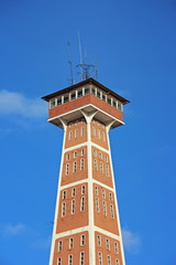 Fototapeta na wymiar Fire tower against the blue sky with clouds.