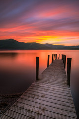Vibrant orange/red long exposure sunset over Derwentwater in the English Lake District. The tourist-popular Ashness jetty can be seen in the foreground.