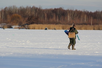 Рыболов с ледобуром и ящиком идет по льду  © demon15