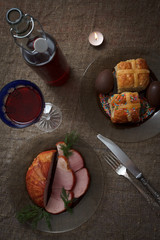 Easter dinner served on burlap tablecloth. Meat, hot cross buns, chocolate eggs and win