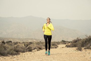 Fototapeta premium attractive sport woman running on earth trail dirty road with desert mountain landscape