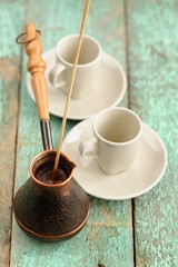 Two cups and copper cezve with fresh black coffee on old wooden