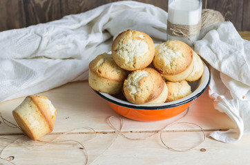 glass of milk with muffins on wooden table