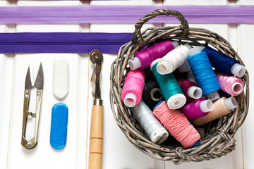 Vintage background with sewing accessories, tools, sewing kit. Scissors, bobbins with thread and needles on the old wooden white background