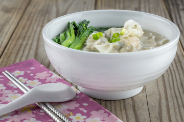 Chinese pork and shrimp dumplings with green vegetables in a broth.